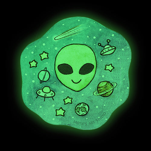 Glow in the dark sticker of an alien with stars, spaceships, and planets surrounding it.