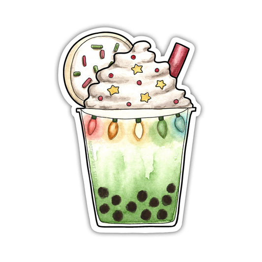 Green tea matcha drink with brown sugar boba, topped with a Christmas sugar cookie and Christmas lights.