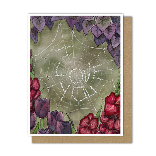 Card with "I love you" written in water droplets in a spiderweb surrounded by purple and red flowers.