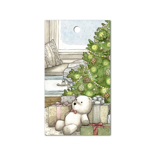 Gift tag with a polar bear stuffed animal sitting underneath a Christmas tree.