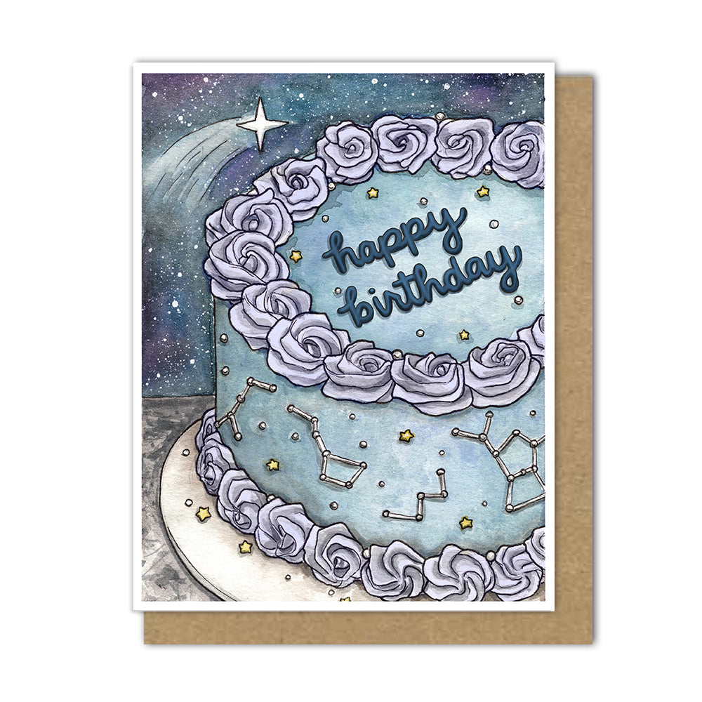 Astrology birthday card with a shooting star crossing over a cake decorated with constellations in icing and a blue galaxy colorway.