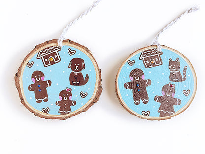 Two wooden ornament side by side showing the different design of the gingerbread cat versus dog design.