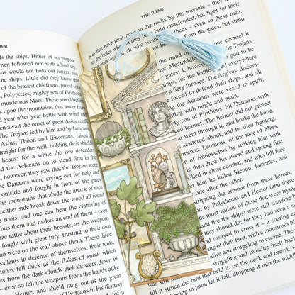 Bookmark with blue tassel featuring a greek mythology inspired bookcase, art, and plants. The bookmark is placed inside a book.