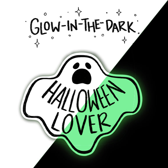 A die-cut sticker shaped like a ghost with the words 'HALLOWEEN LOVER' in black lettering, shown on a split white and black background with the text 'GLOW-IN-THE-DARK' above it. The sticker is half white and half bright neon green, with a black outline and a glowing effect.