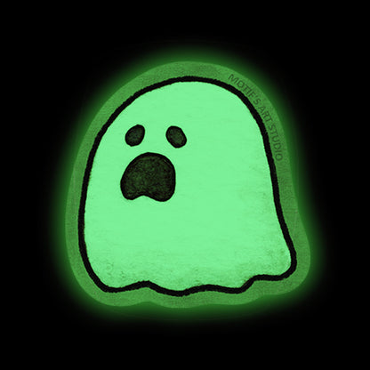 A glowing green ghost-shaped sticker with a moaning face, outlined in black, centered on a black background.