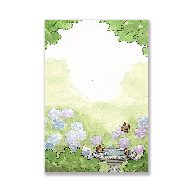 Notepad of a garden scene with a birdbath, little brown birds, and purple and blue hydrangeas.