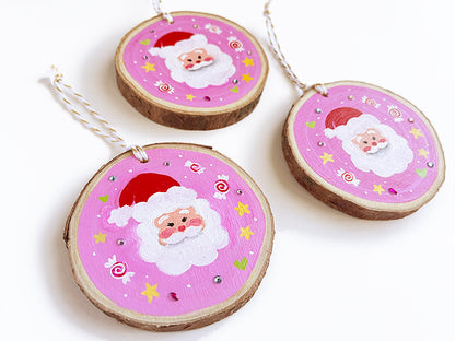 Angles view of wooden ornaments with Santa Clauses on a pink background.