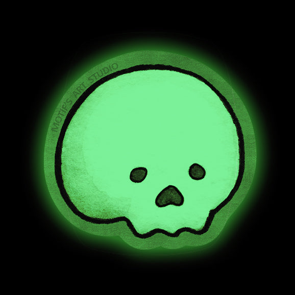 A glowing green skull sticker with a black outline and small dark eyes and nose on a black background. 