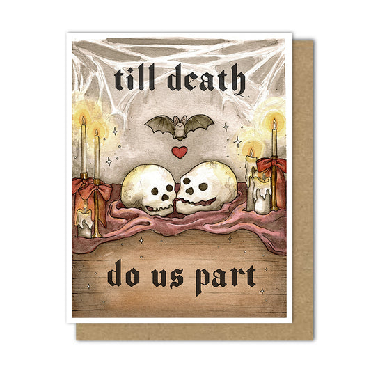 An A2 greeting card with a kraft envelope behind it. The card artwork shows two skulls resting on a maroon cloth, with candles, a bat, stars, and the gothic text 'till death do us part' in a dark, romantic setting.