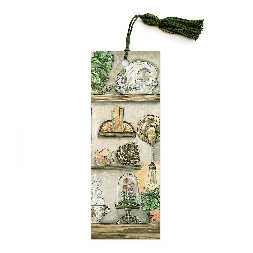 bookmark with shelves of skull, books, lighting, plants and mushrooms with green tassel