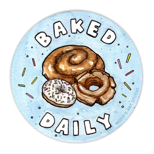 A circle sticker with 3 painted classic donuts surrounded by sprinkles on a blue background. The sticker says Baked Daily.